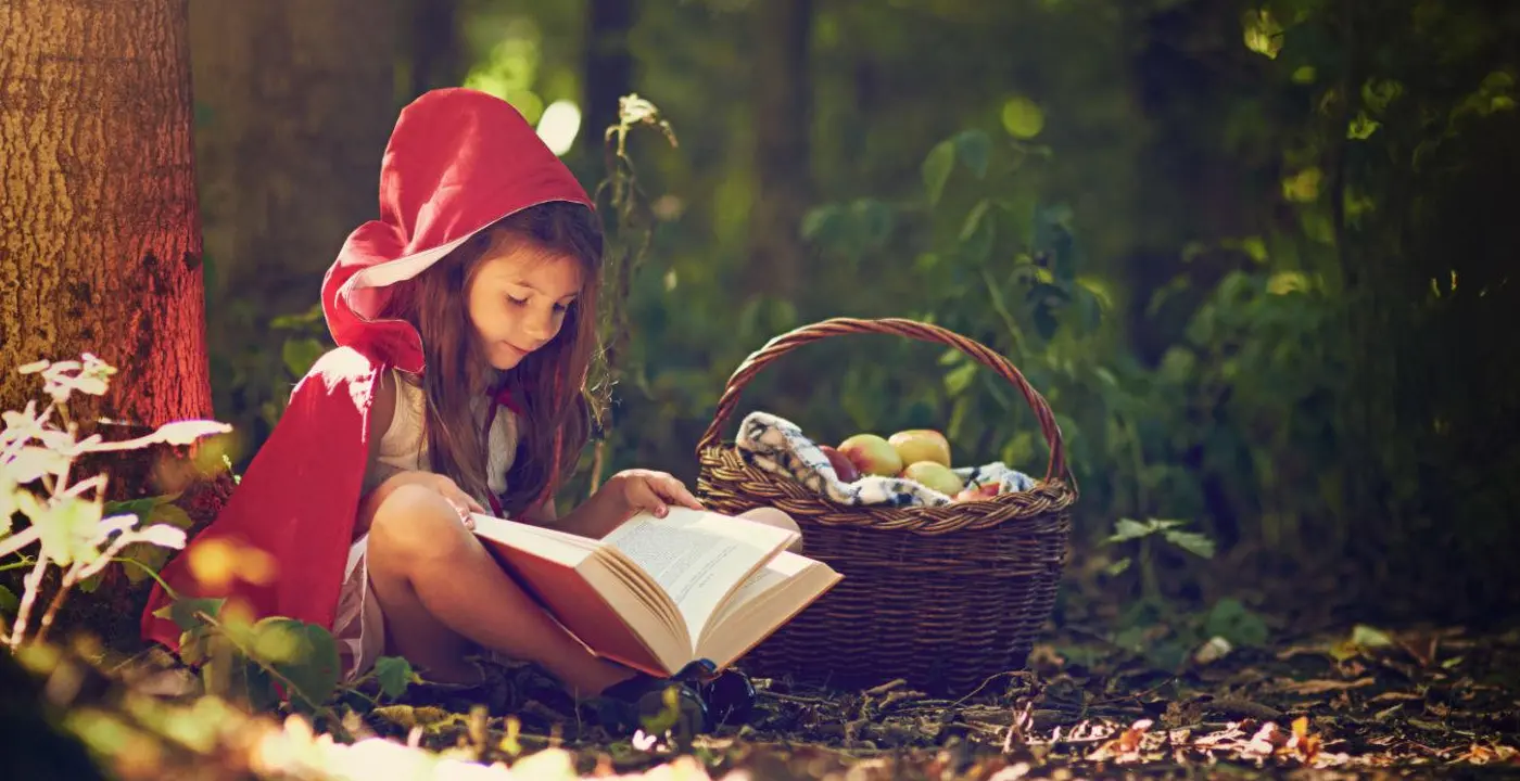 child reading fairy tale with dark character themes in forest setting
